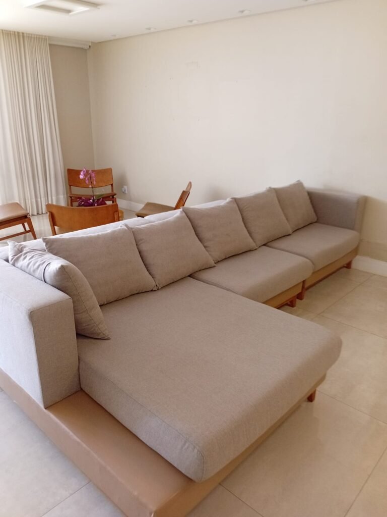 Sofá de canto com chaise em tecido bege claro, em sala residencial, referência para higienização de estofados em São José dos Campos SP.